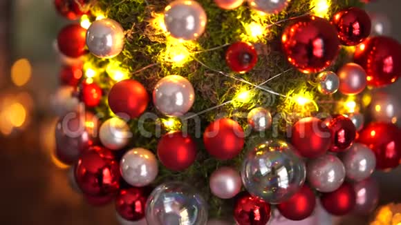 漂亮的小圣诞树的苔藓在木桌上心情愉快加兰灯在背景上抽象模糊视频的预览图