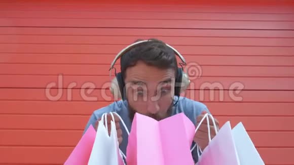 英俊的男人拿着一堆彩色纸袋红色背景上带着困惑的情绪脸是这些礼物吗视频的预览图