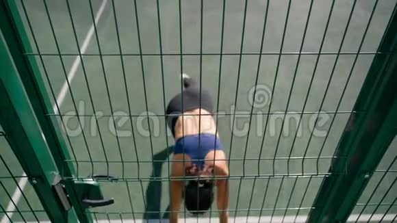 那个女孩站在她的手上倒在篱笆附近操场上的围栏网视频的预览图