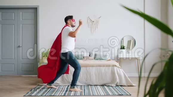 穿着红色斗篷和面具的超级英雄在家里的卧室里跳舞视频的预览图