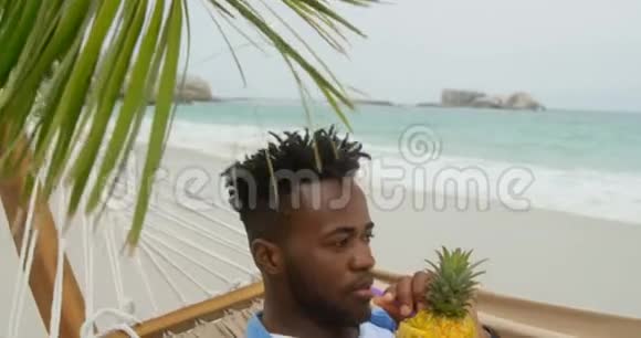 在海滩上喝菠萝汁的非裔美国人的正面景色视频的预览图