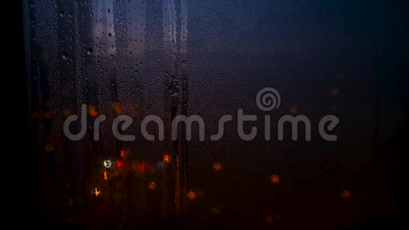 随着城市灯光模糊的背景雨季玻璃窗户上的雨滴被关闭概念视频的预览图
