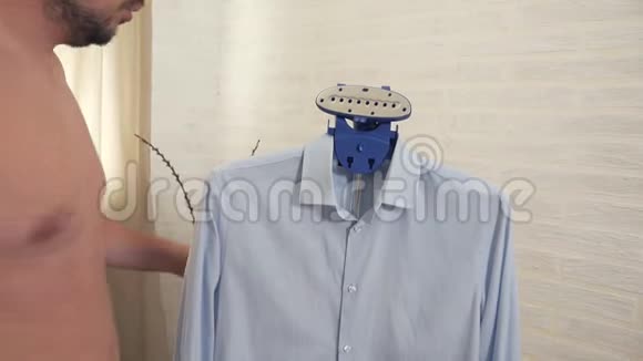 一个男人在家中抚摸蒸煮一件蓝色衬衫视频的预览图