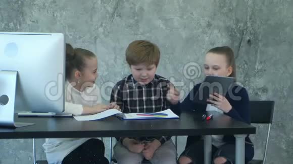 三个小孩子在办公室里开商务会议用平板电脑和文件分享想法视频的预览图