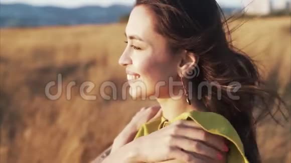 金色阳光下微笑的女人的肖像风吹她的头发慢动作视频的预览图