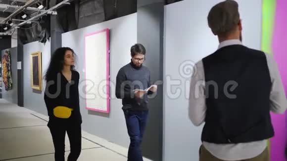 男导游正在为两位参观美术馆和展示图片的游客讲话视频的预览图