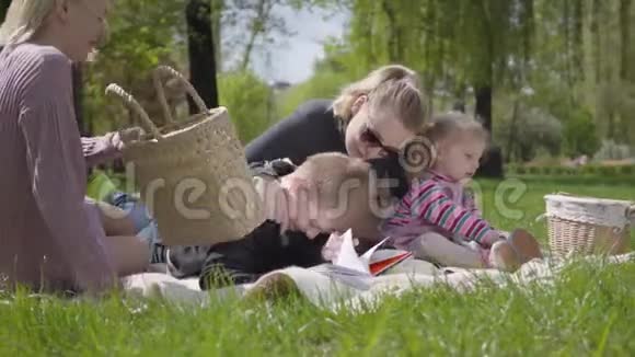 肖像漂亮的家庭户外娱乐两位美丽的年轻母亲和他们的孩子在公园野餐一个男孩视频的预览图