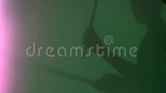 绿色墙壁背景上的鼓棒青年鼓手剪影侧视概念男影假装打鼓视频的预览图