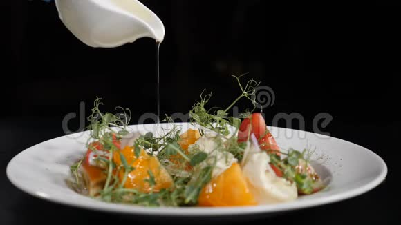 厨师在黑色背景的新鲜蔬菜沙拉上浇酱汁特写镜头用酱汁煮沙拉程序视频的预览图