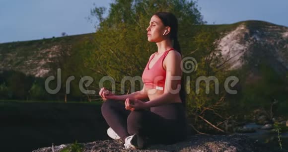 漂亮的女人在山中央的河顶上做瑜伽冥想她集中精力视频的预览图