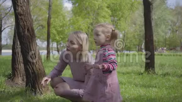 可爱的小女孩和她的母亲在公园里玩用小手指指着女人在解释她的孩子视频的预览图