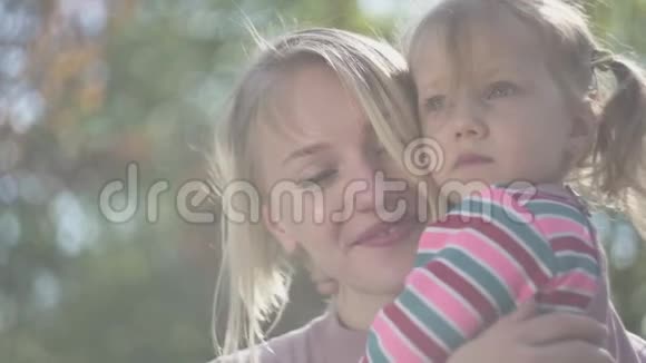 年轻母亲和美丽的金发女儿在母亲手中的肖像视频的预览图