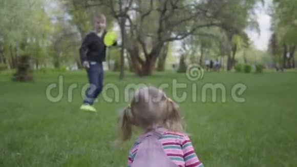 哥哥和妹妹跑在美丽的绿色公园里小女孩摔倒了男孩帮她站起来快乐视频的预览图