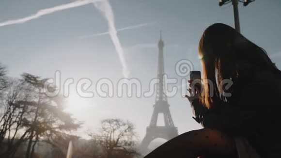 快乐年轻的女博主带着手机在度假慢动作拍日落巴黎埃菲尔铁塔全景照片视频的预览图