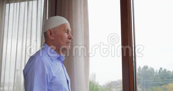 年长的男人透过窗户看视频的预览图