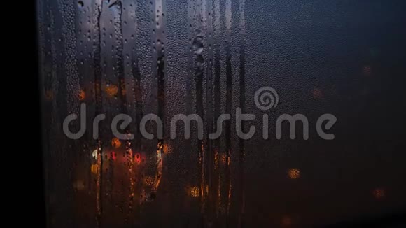在模糊的灯光背景下窗户上的雨污特写概念雨滴滴在背景上的窗户上视频的预览图