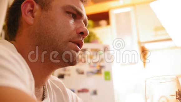 一个严肃的年轻人坐在家里厨房的画像视频的预览图