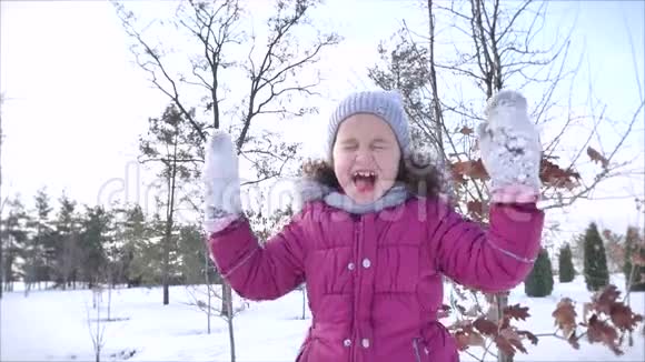 在阳光明媚的冬日户外快乐的童年快乐的小女孩一边开心和微笑着看着镜头视频的预览图