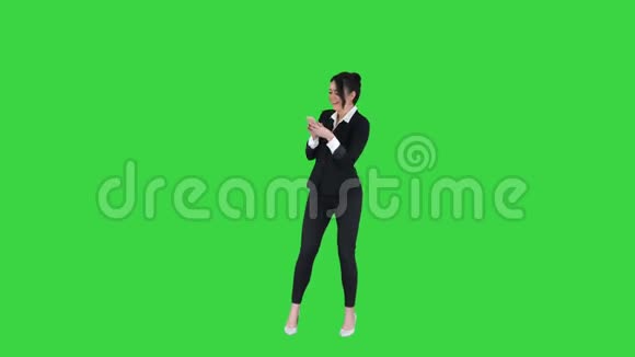 快乐的年轻女子在正式的舞蹈和使用手机上的绿色屏幕Chroma键视频的预览图