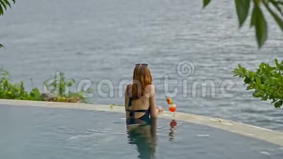 美国女人在巴厘岛度假胜地的游泳池里喝鸡尾酒度过一个愉快的假期视频的预览图