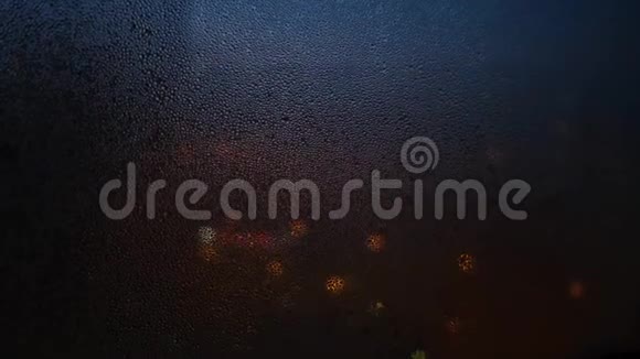 在模糊的灯光背景上用雨滴关上窗户概念昏暗的灯光透过昏暗的窗户照进来视频的预览图