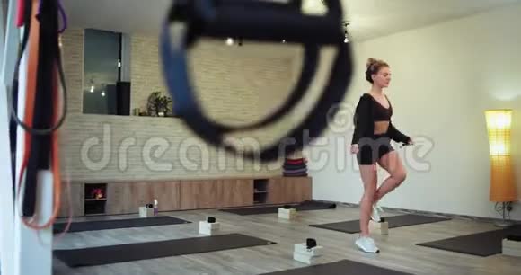 一位穿着运动服用绳子跳跃以获得更多肌肉的迷人金发女士非常集中在一个大型有氧运动中视频的预览图