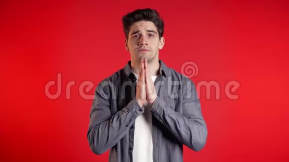 穿衬衫的帅哥在红色背景下祈祷欧洲种族的家伙求人视频的预览图