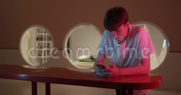 时尚的米莉妮亚人用他的智能手机在霓虹灯照明处站在室内的架子上屏幕视频的预览图