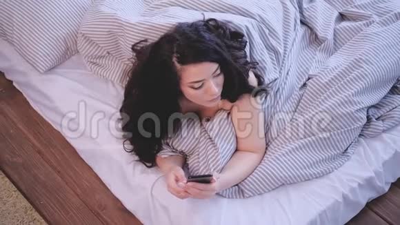 早晨习惯体贴的女人智能手机床视频的预览图