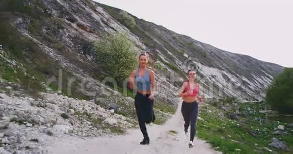 两位深黑肤色的女士在山中央用石块使劲地跑着她们很高兴在那里一起享受锻炼视频的预览图