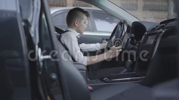 穿着西装的可爱小男孩坐在车里研究沙龙孩子长大了视频的预览图