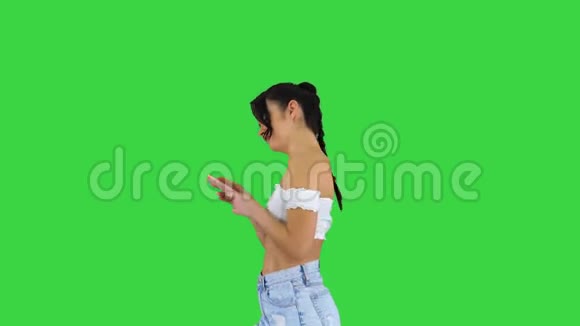 可爱的女孩检查她的手机并在绿色屏幕上跳舞Chroma键视频的预览图