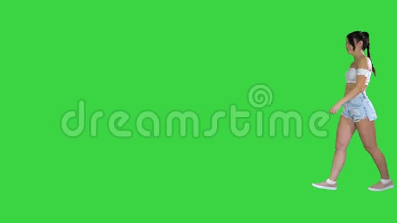 可爱的西班牙裔女模特穿牛仔短裤在绿色屏幕上跳舞Chroma键视频的预览图