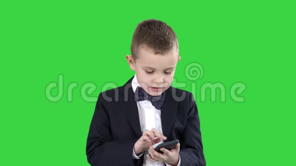 聪明的男孩在绿色屏幕上发短信玩网络游戏发送图片下载音乐和电影视频的预览图