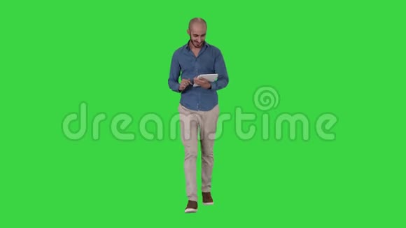阿拉伯男人在绿色屏幕上行走和使用平板电脑上网Chroma键视频的预览图