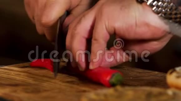 雄性手在橡木板上把红辣椒切成小圆圈的特写镜头库存录像元素视频的预览图