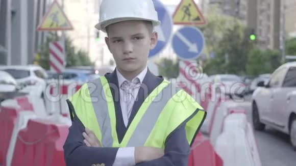 肖像可爱的小秘密男孩穿着商务服安全设备和建筑工人头盔站在繁忙的地方视频的预览图