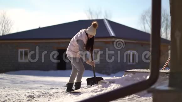 在房子附近的后院铲雪的年轻女人视频的预览图