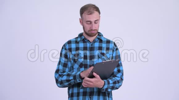 快乐的留胡子的嬉皮士男子在剪贴板上阅读并竖起大拇指视频的预览图