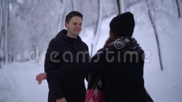 漂亮的年轻女人跑到那个家伙身边跳进他的怀里在冬季公园一个男人抓住他的女朋友他们拥抱视频的预览图