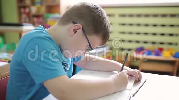 小学时一个戴眼镜的男孩用铅笔在笔记本上写字解决了逻辑和逻辑问题视频的预览图
