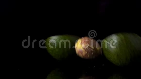 一种成熟的绿色鳄梨在黑暗的背景下缓慢地落在桌子上视频的预览图