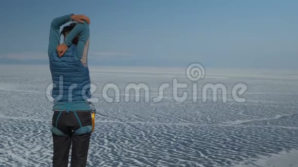 一个年轻的女人站在冰冻的湖岸上做热身视频的预览图