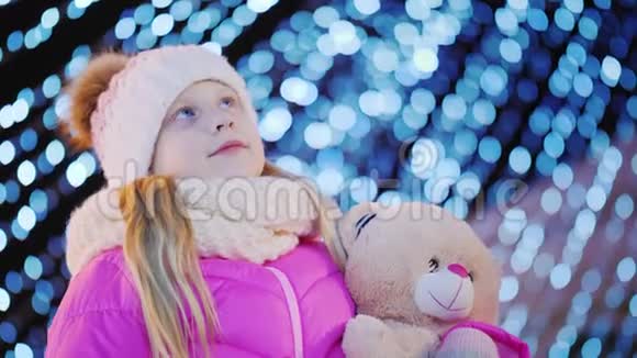一个手里拿着玩具的孩子抬头看着圣诞树视频的预览图