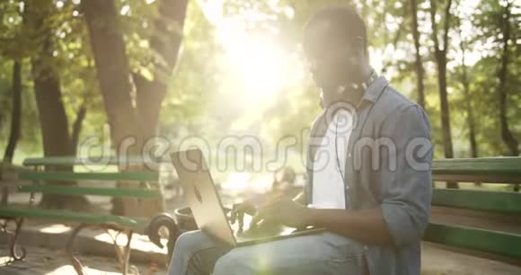 男子在公园夕阳下的膝上工作视频的预览图