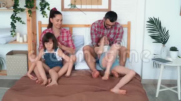 父母给女儿挠痒痒坐在床上开怀大笑家庭幸福视频的预览图