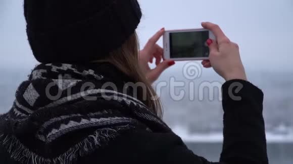 后景年轻女子戴着冬帽和保暖外套拍摄美丽的风景背景模糊女孩视频的预览图