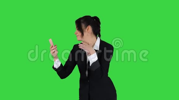 商务女性看智能手机预演和跳舞的绿色屏幕铬键视频的预览图