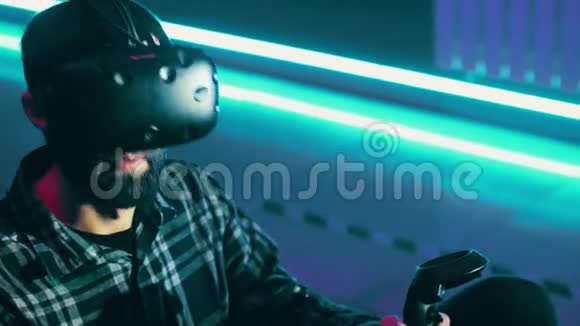 大胡子男子使用现代虚拟现实耳机与游戏垫玩虚拟现实游戏视频的预览图