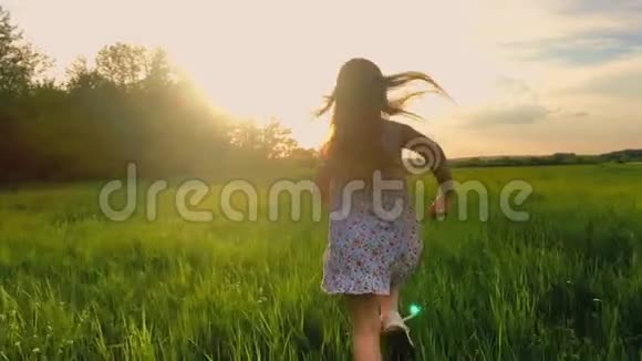 日落后拍摄的可爱少年女孩穿着连衣裙奔跑在绿色草地上120英尺慢速运动视频的预览图